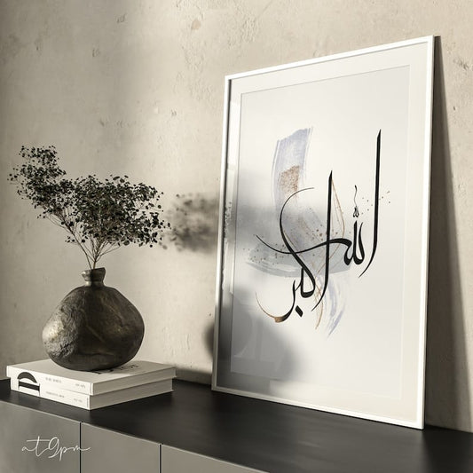 Framed artwork with Arabic calligraphy on a wall next to a vase and books.