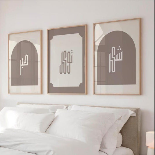 Three framed artworks with Arabic calligraphy above a bed in a bedroom.