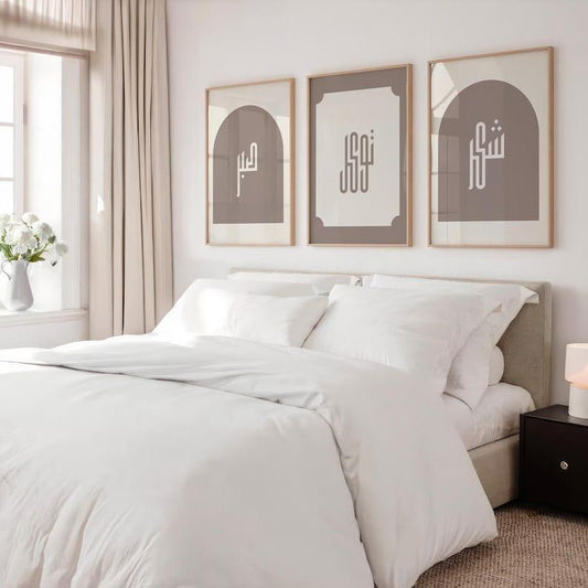 Neatly made bed with white bedding in a bedroom setting, featuring three framed artworks on the wall.